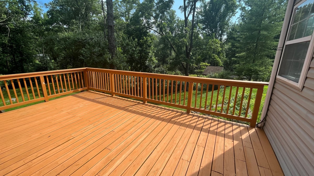 Finished wooden deck with sliding glass doors overlooking backyard